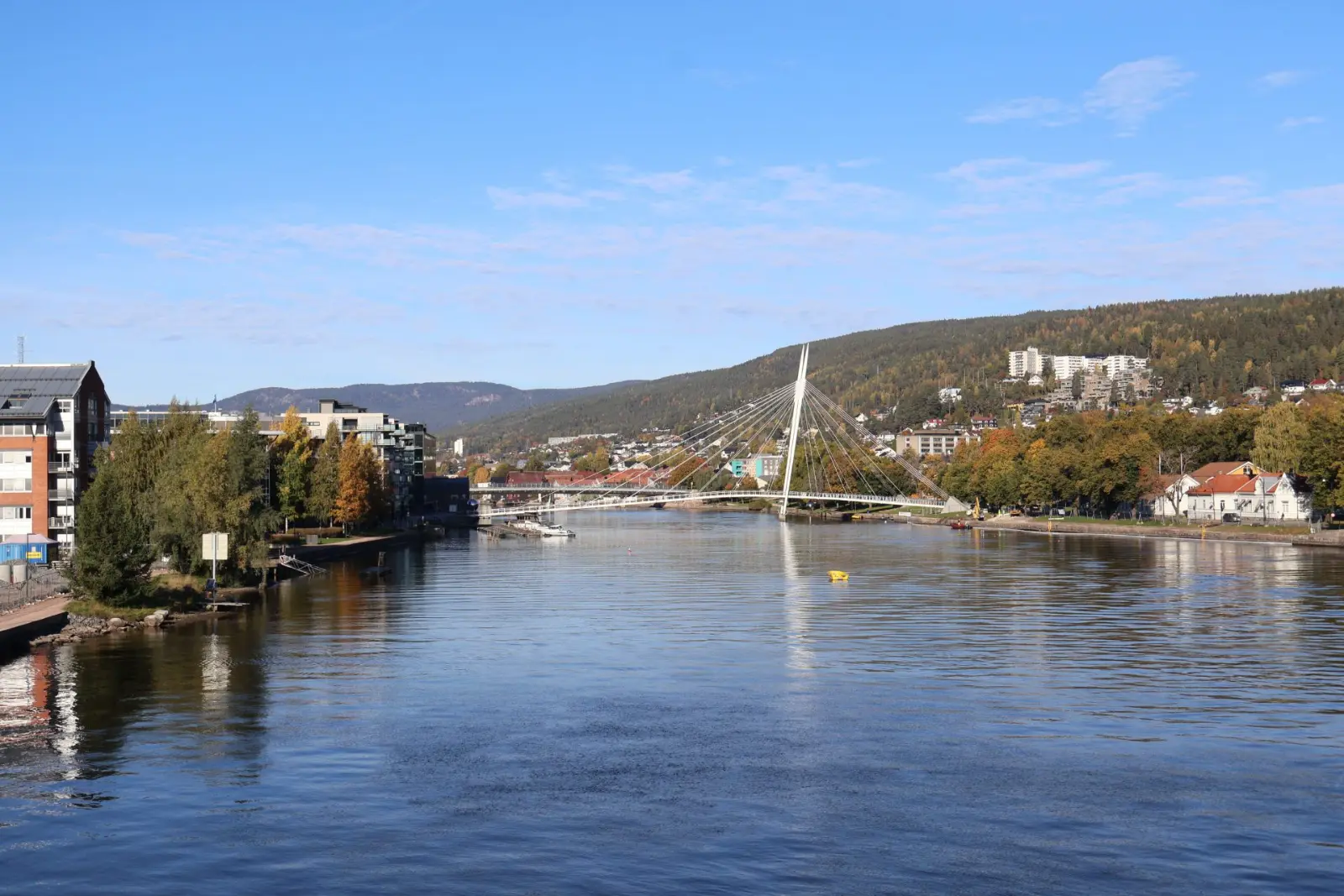 Drammenselva gjennom Drammen sentrum med gang- og sykkelbrua Ypsilon, høstfarger og Bragernesåsen i bakgrunnen