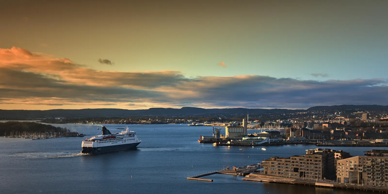 Oslo havn og indre Oslofjord i kveldslys, med ferge på vei inn mot Bjørvika og Sørenga